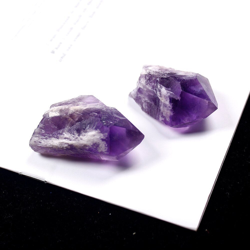 Two amethyst crystal points natural with deep purple hues on white surface by Sacred Moon Candle Co