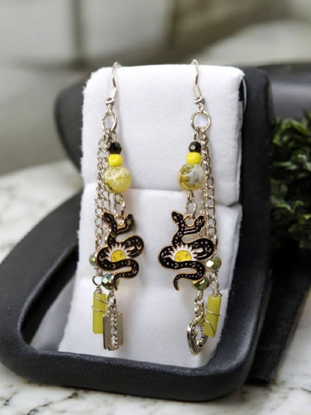 Snake charm earrings by Sacred Moon Candle Co with yellow beads and silver chains in black jewelry box