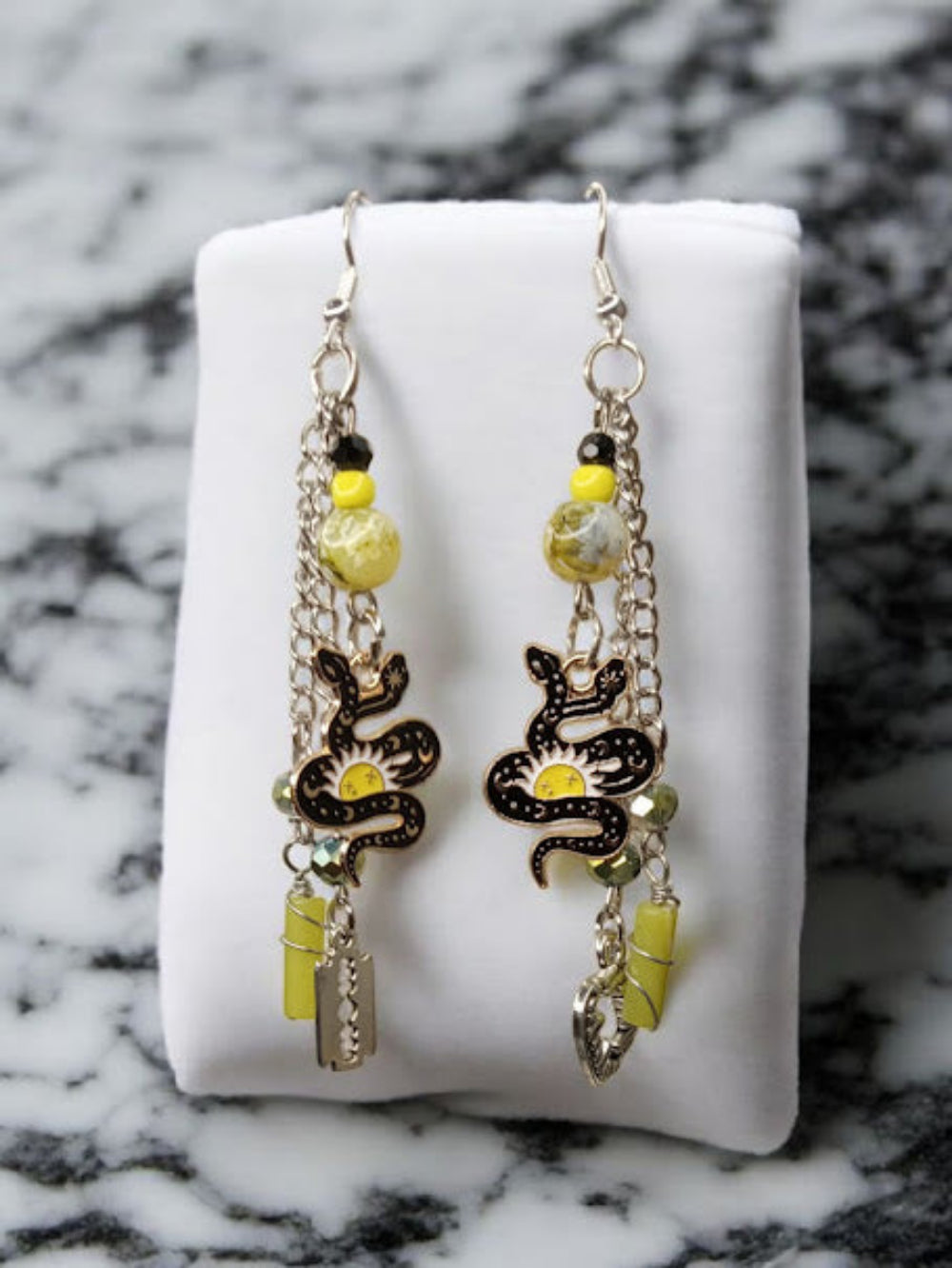 Sacred Moon Candle Co snake charm earrings with black and yellow beads and silver chains