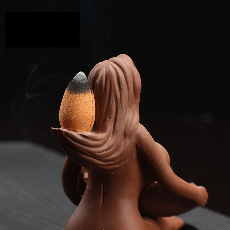 Ceramic sea goddess incense burner in terracotta brown holding burning incense cone with smoke