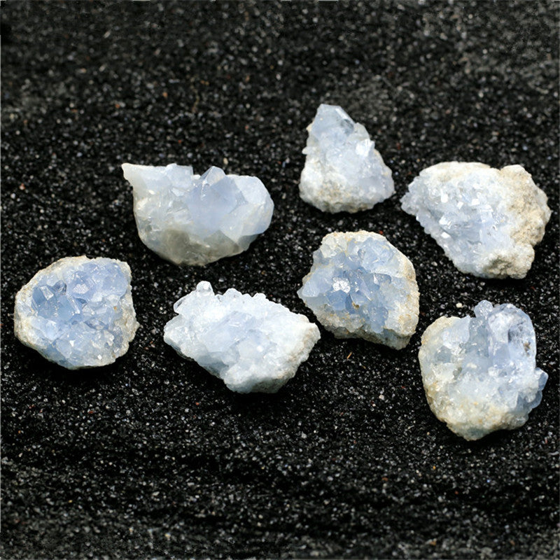 Seven pale blue celestite kyanite crystal stone clusters on black sand for healing decor