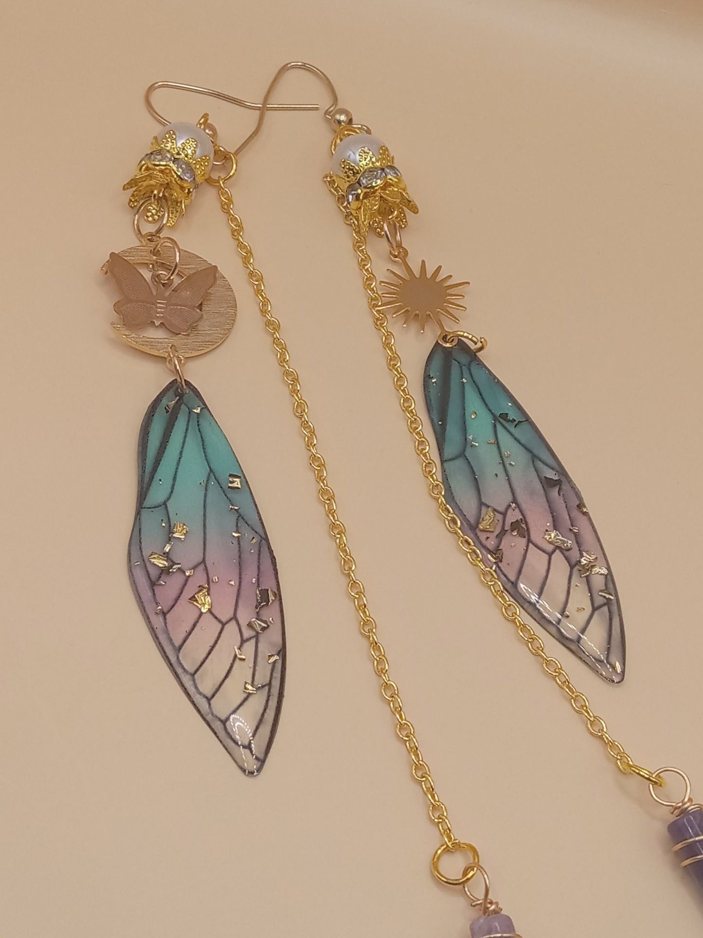 Sacred Moon Candle Co blue and violet fairy earrings with gold chains wing shaped charms butterfly and sun accents