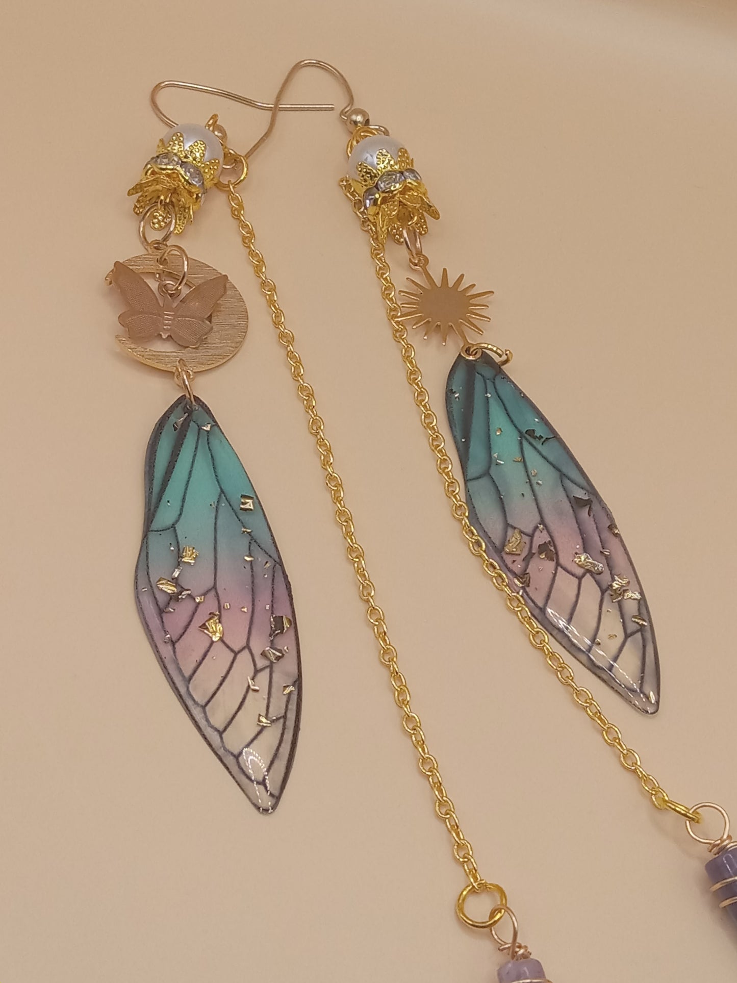 Sacred Moon Candle Co blue and violet fairy earrings with gold chain sun and butterfly charms and resin wing drops