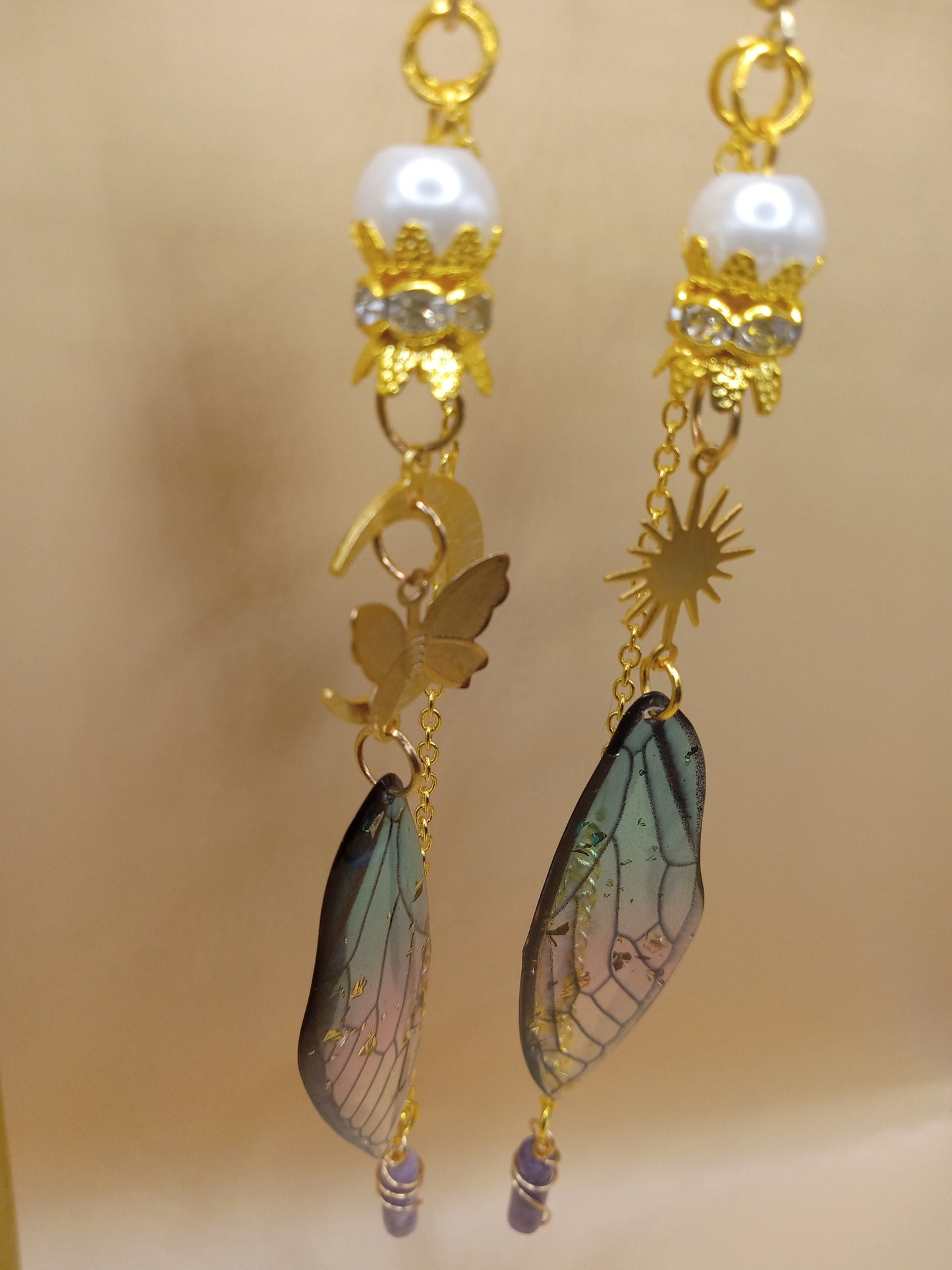 Sacred Moon Candle Co blue and violet fairy earrings with gold butterfly and sun charms and iridescent wing drops