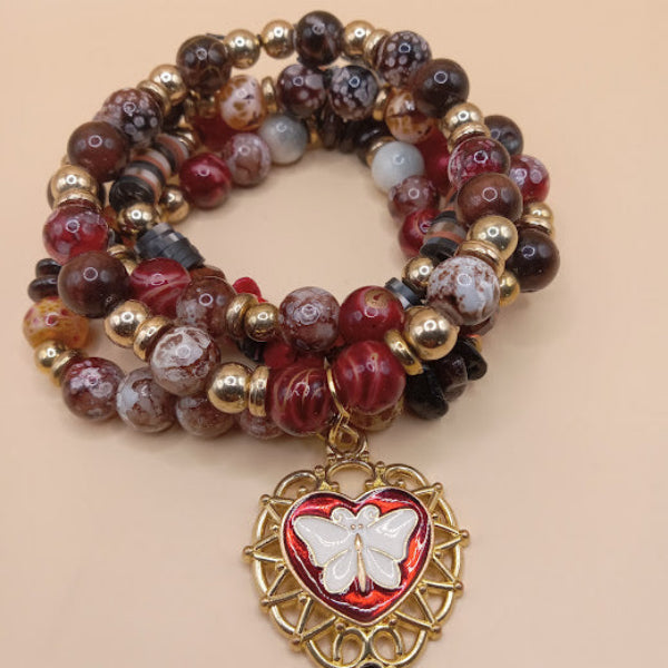 Moth and flame bracelet stack with multicolored beads and a gold heart pendant from Sacred Moon Candle Co