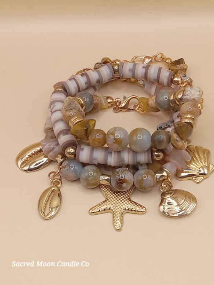 Bohemian natural stone bracelet stack with gold charms including starfish and shells by Sacred Moon Candle Co