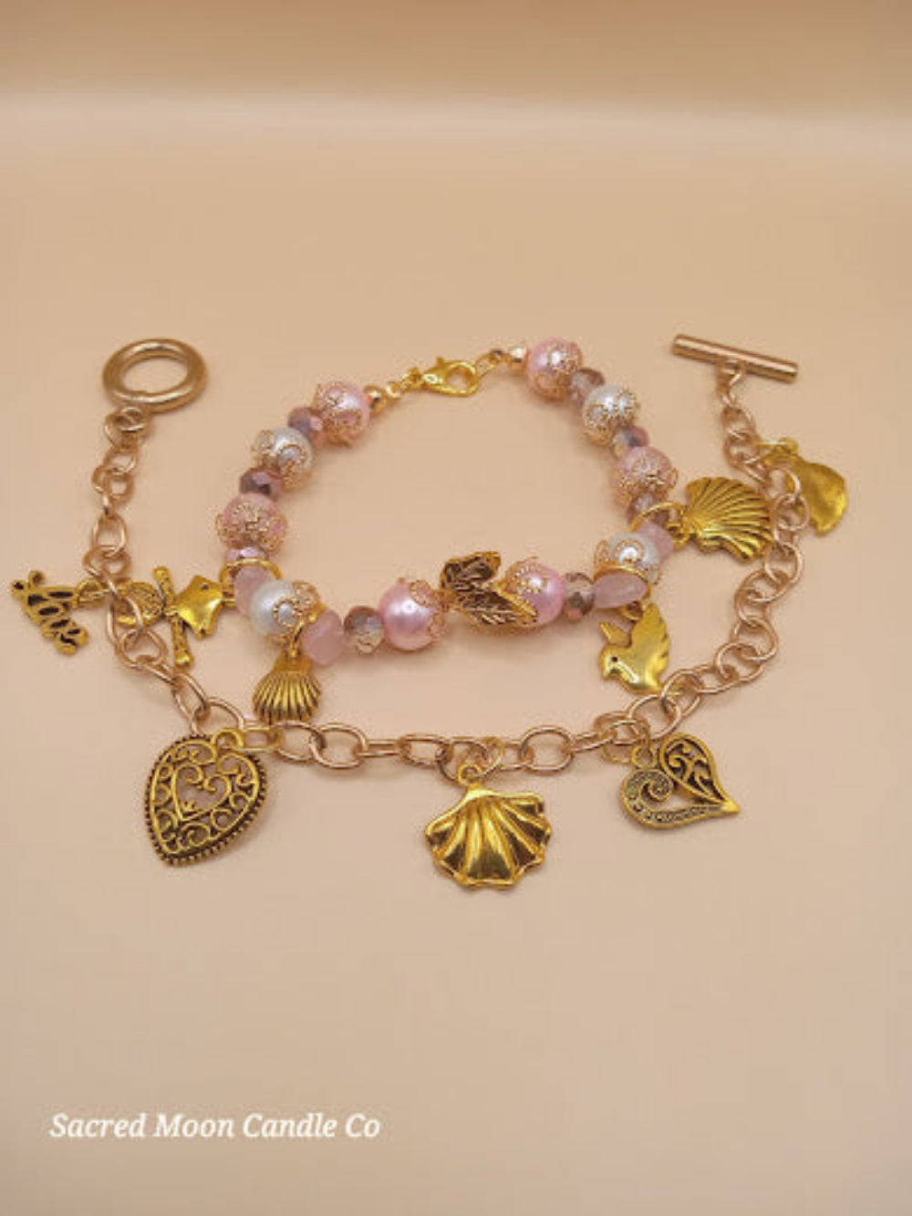 Aphrodite bracelet set by Sacred Moon Candle Co with gold charms and pink beaded bracelet stack