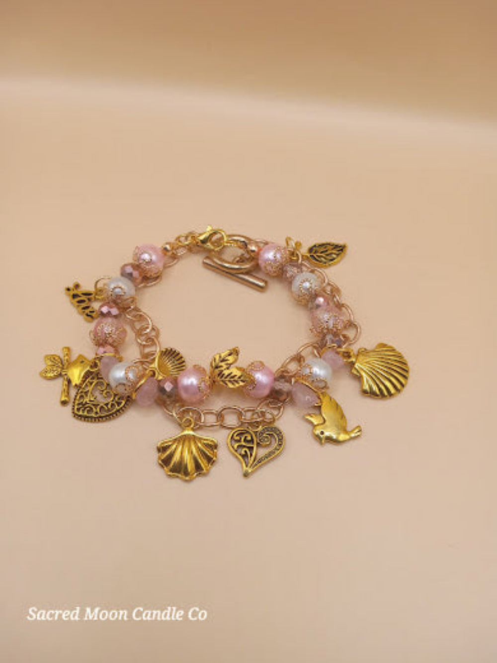 Aphrodite bracelet set from Sacred Moon Candle Co featuring gold charms and pink beads bracelet stack
