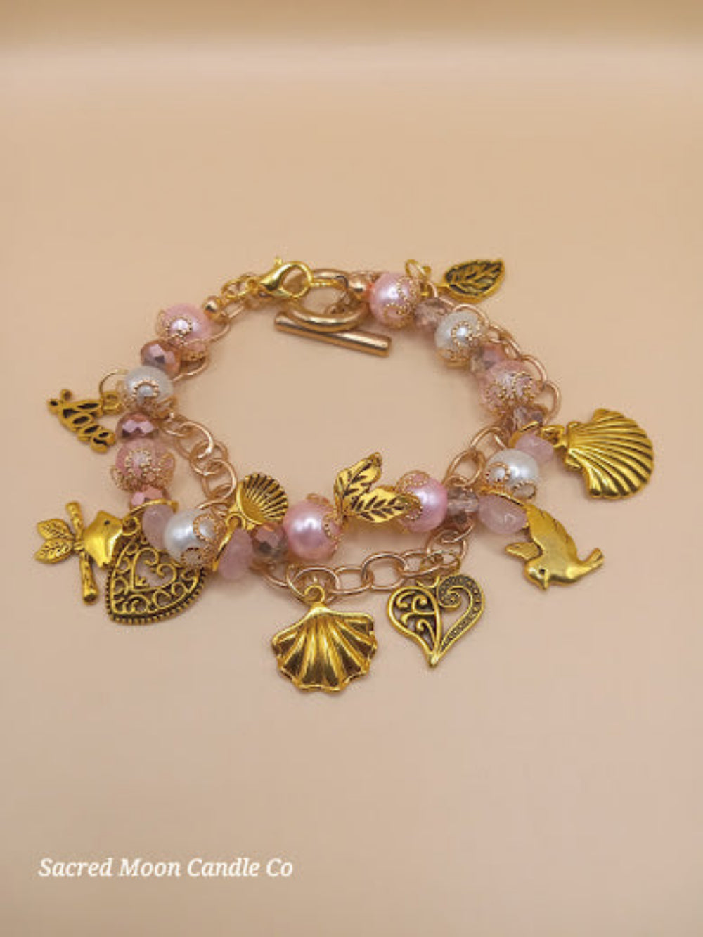 Aphrodite bracelet set by Sacred Moon Candle Co featuring gold charms and pink beads in a stacked design