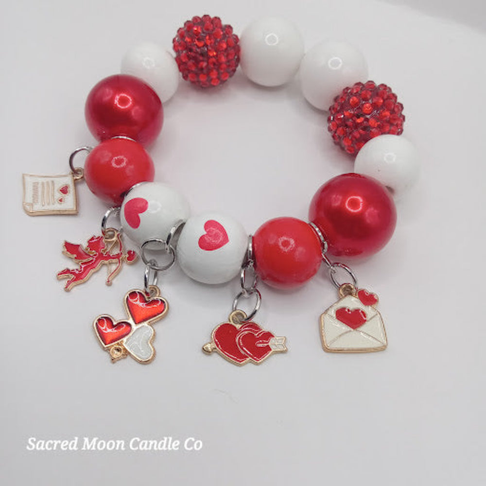 Cupid themed bubblegum beaded bracelet with red and white beads and heart charms by Sacred Moon Candle Co