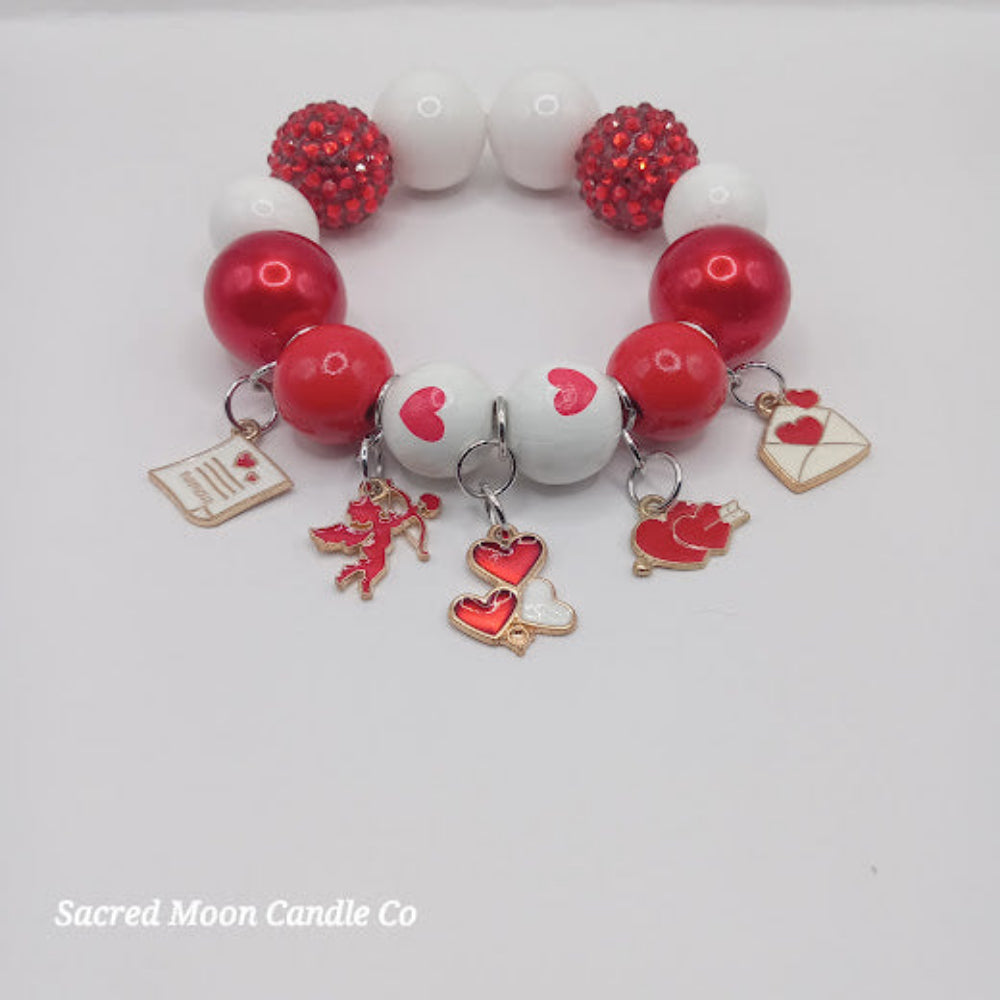 Cupid themed bubblegum beaded bracelet by Sacred Moon Candle Co with red white beads and love charms