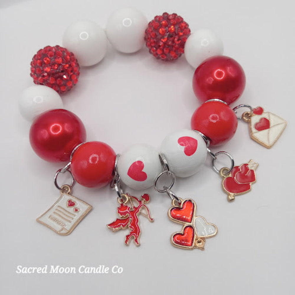 Cupid themed bubblegum beaded bracelet with red and white beads and love charms by Sacred Moon Candle Co