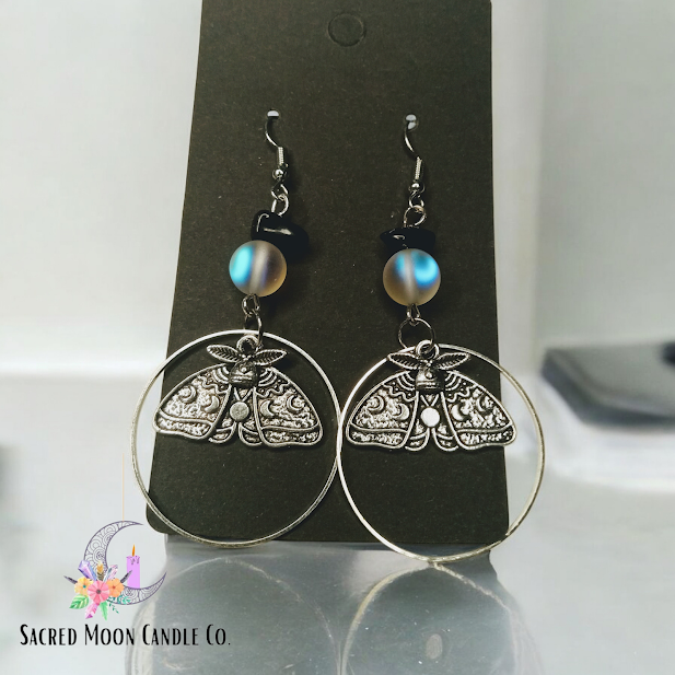 Sacred Moon Candle Co celestial moth dangle earrings with intricate silver moth design and blue bead accents