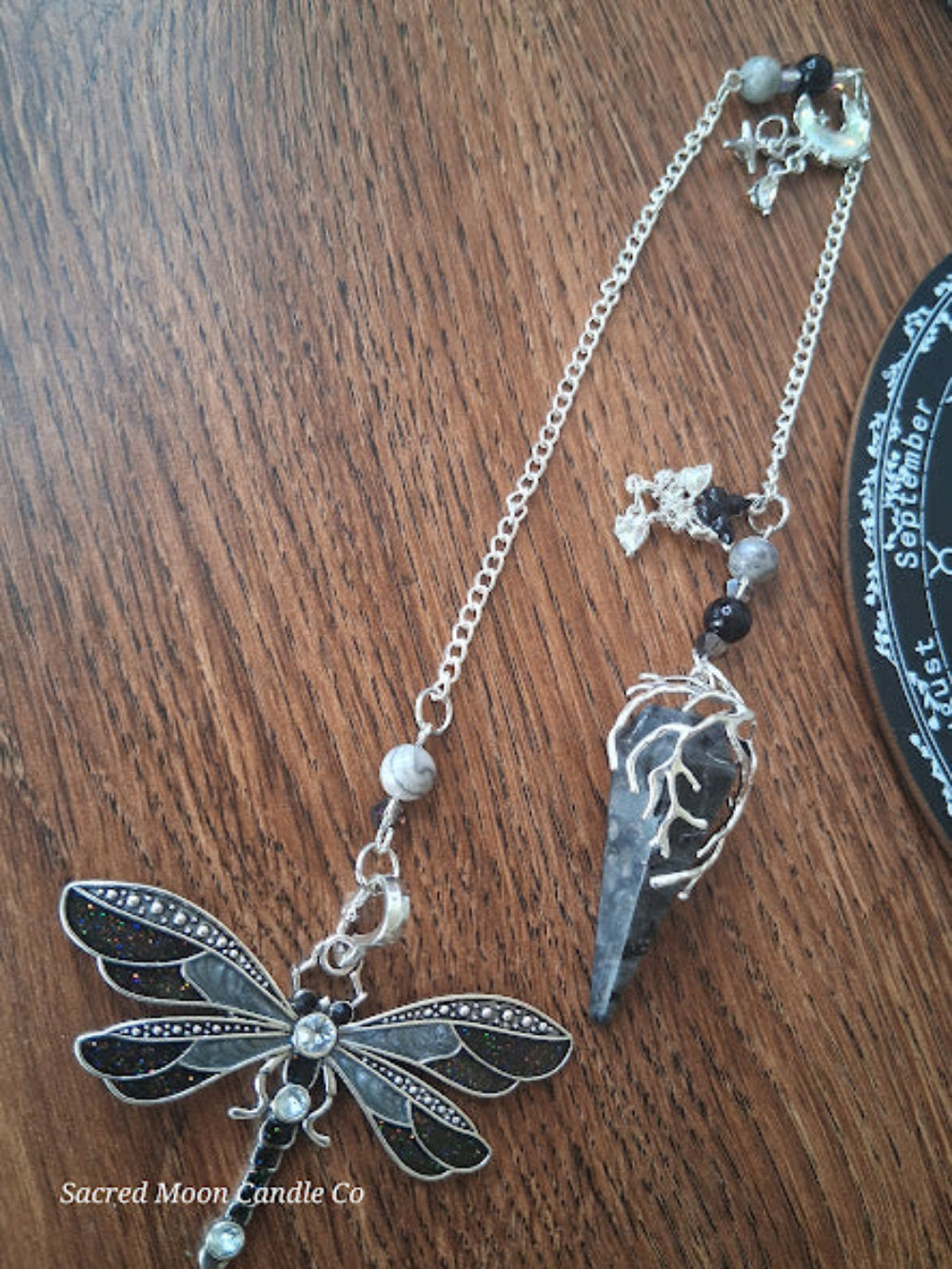 Larvikite moon pendulum with silver dragonfly charm on chain from Sacred Moon Candle Co altar tools
