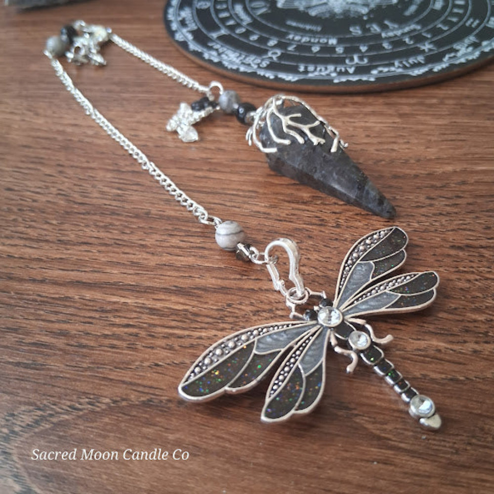 Larvikite moon pendulum with dragonfly charm and tree of life on wooden surface by Sacred Moon Candle Co