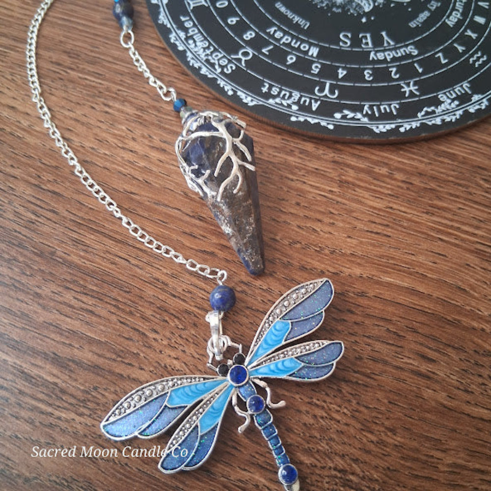 Sodalite and lapis lazuli pendulum with dragonfly design and silver chain on wooden surface