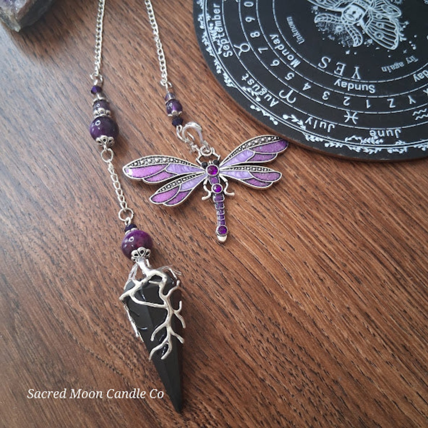 Black tourmaline Purple Tigers Eye Dragonfly Pendulum altar tool with purple accents on wooden surface
