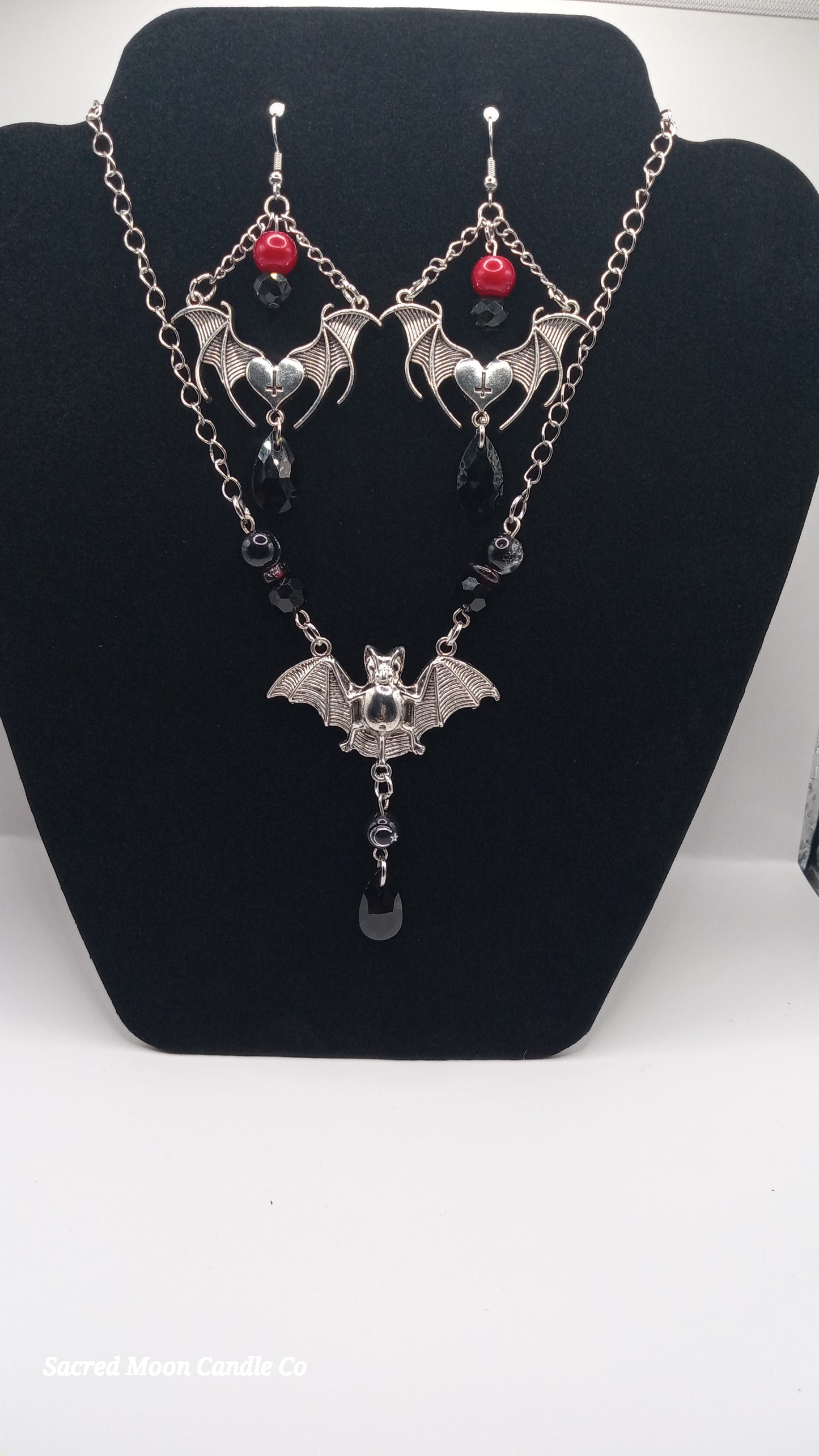 Sacred Moon Candle Co gothic bat jewelry set featuring silver bat earrings and matching necklace with red and black beads