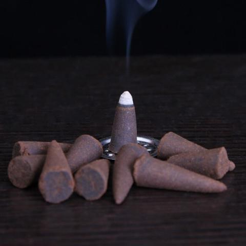 Sacred Moon Candle Co safflower musk incense cones arranged with one burning and releasing smoke