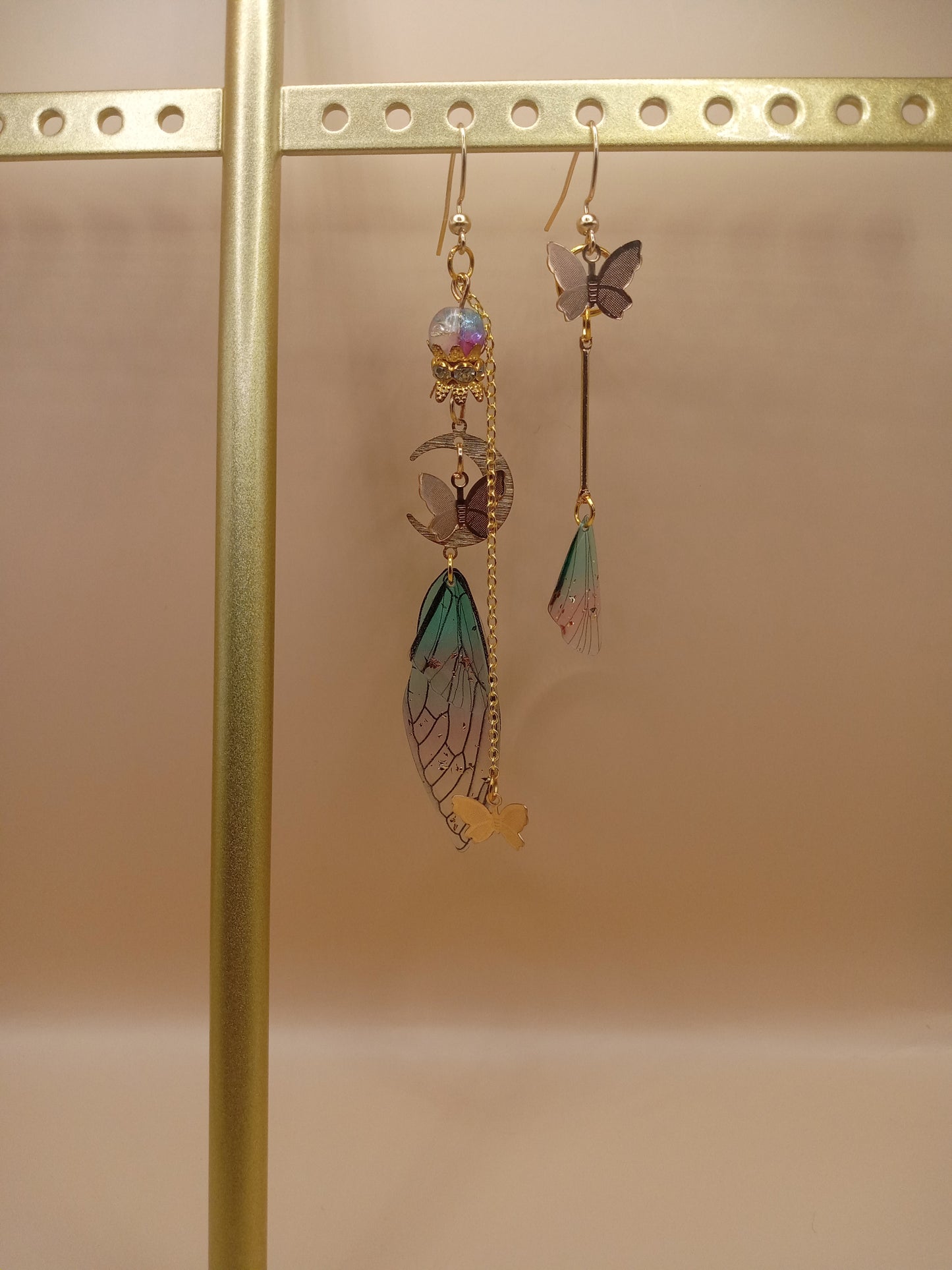 Sacred Moon Candle Co fairy wing earrings with gold chains and colorful wing charms