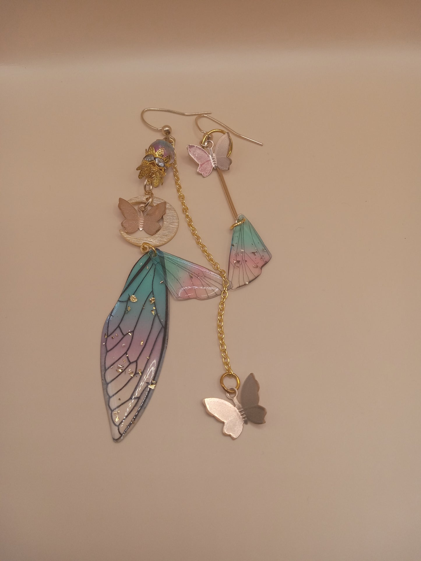 Sacred Moon Candle Co fairy wing earrings featuring pastel blue and pink wing design with gold chains and butterfly accents