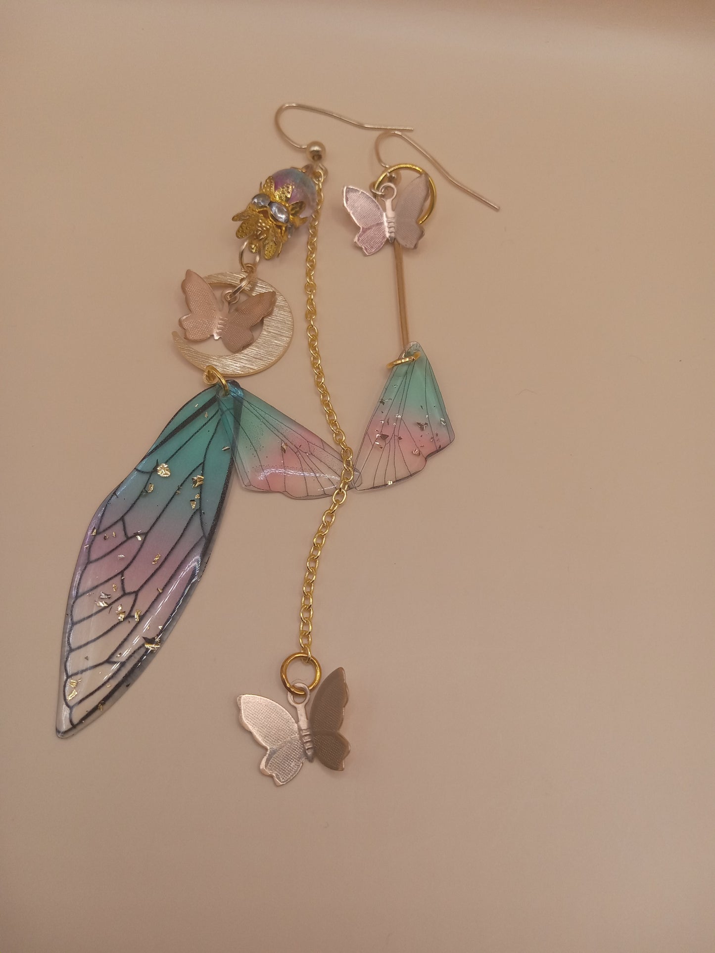 Sacred Moon Candle Co fairy wing earrings with pastel butterfly and wing designs on gold chains