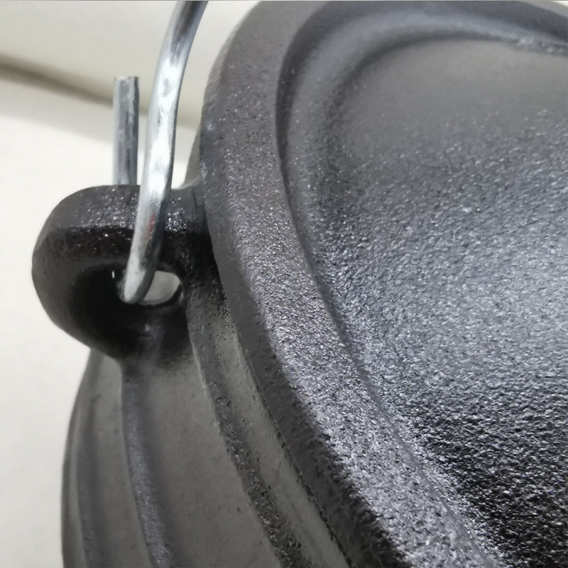 Close-up of Sacred Moon Candle Co three-legged cast iron cauldron black handle and textured surface