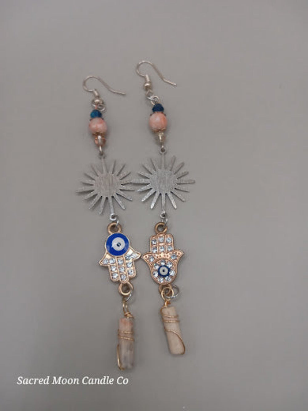 Sacred Moon Candle Co Sunburst Hamsa evil eye earrings with silver sunburst, blue and pink beads, and crystal accents