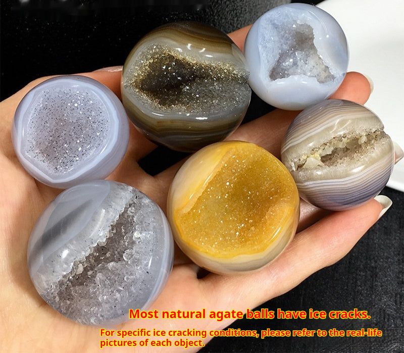Hand holding natural agate crystal ball for altar with various colors and sparkling geode interiors
