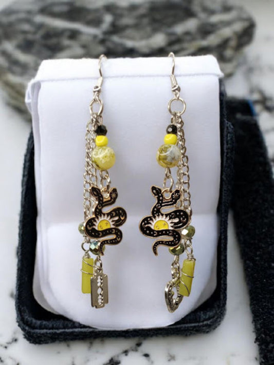 Sacred Moon Candle Co snake charm earrings with black and yellow beads and dangling charms on silver chains