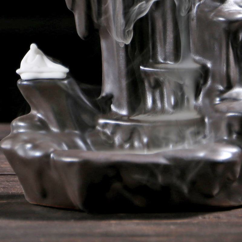 Sacred Moon Candle Co black backflow incense burner with smoke flowing down dark sculpted surface