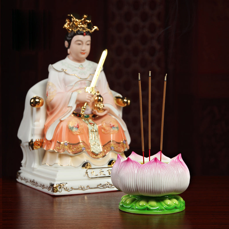 Ceramic lotus incense burner holding three burning incense sticks on a wooden table