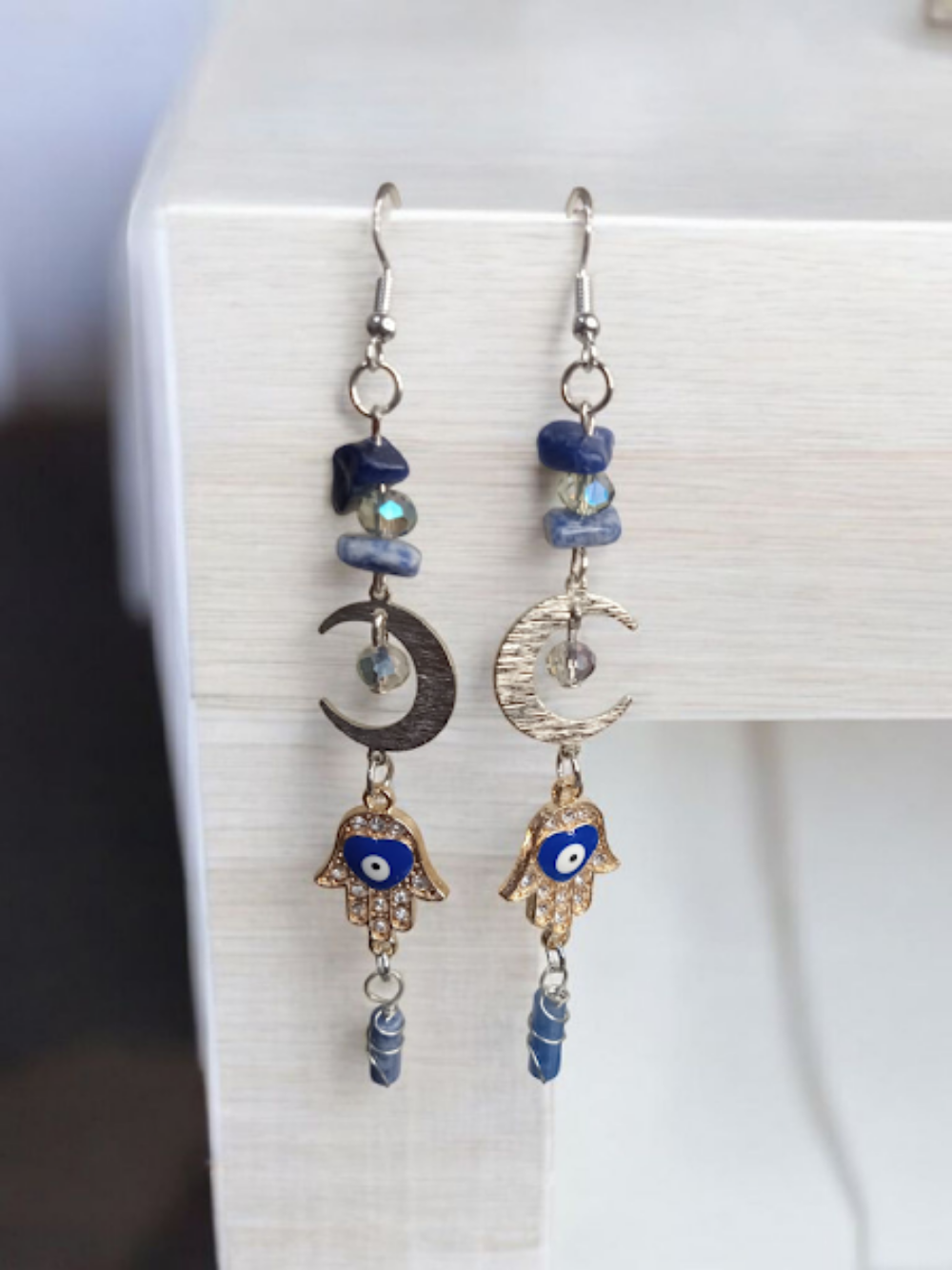 Sacred Moon Candle Co crescent moon hamsa earrings with blue stones and gold-tone charms