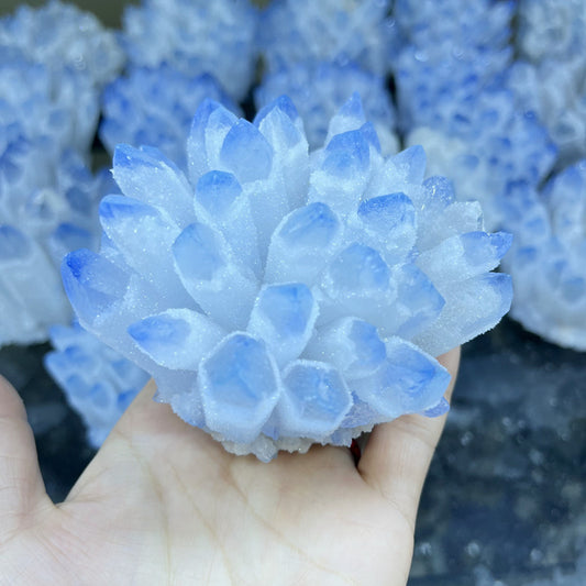 Hand holding Blue Phantom Crystal Quartz Cluster with pale blue tips sparkling for altar tools