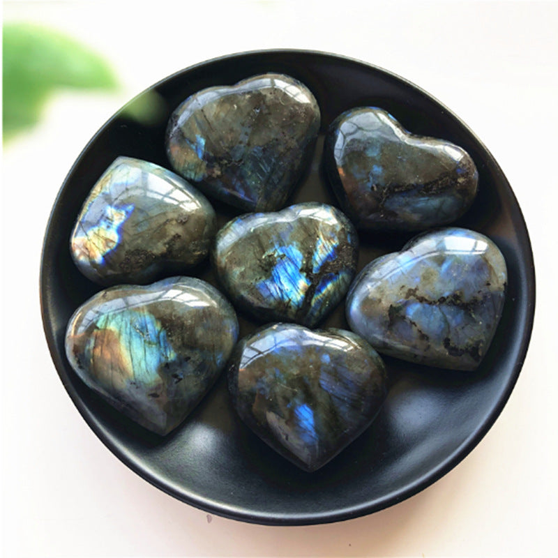Set of seven polished labradorite heart crystal stones in black bowl showing blue flash iridescence