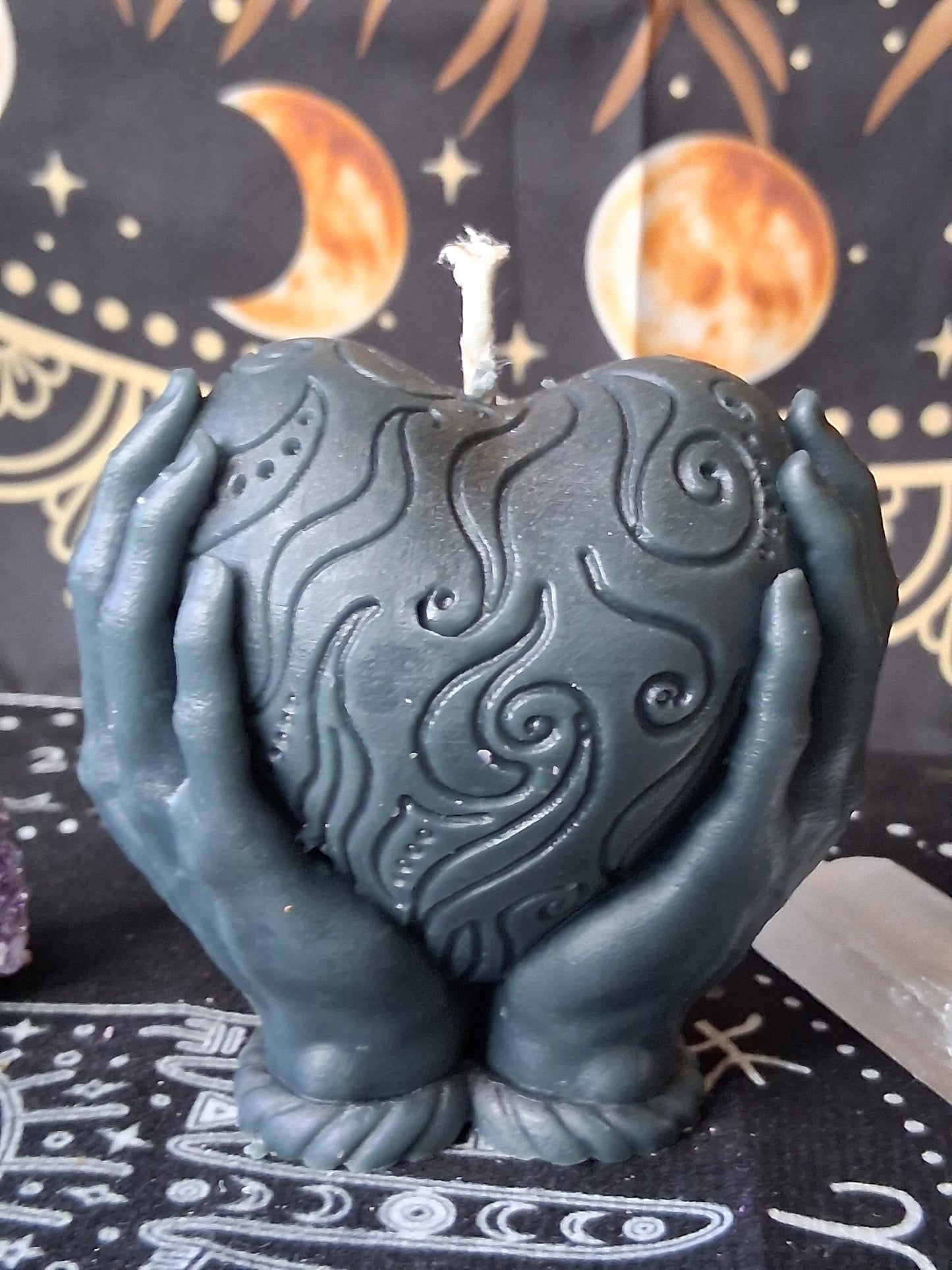 Heart in hands candle by Sacred Moon Candle Co with intricate swirling patterns in dark gray
