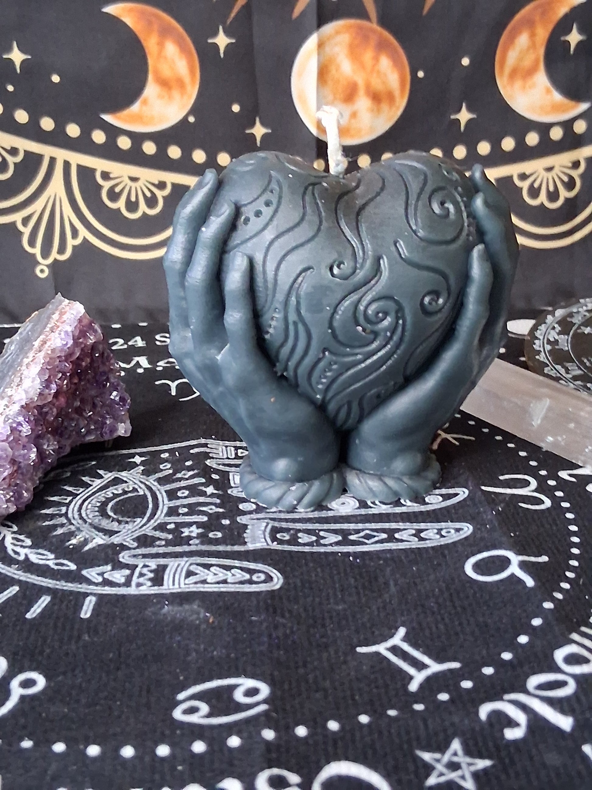Heart in hands candle by Sacred Moon Candle Co with intricate swirl design on black background