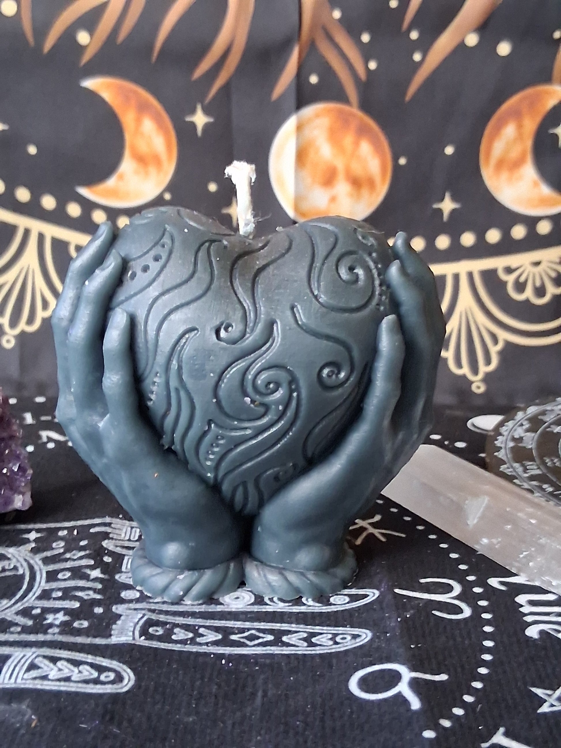 Sacred Moon Candle Co heart in hands candle in dark gray with intricate swirling patterns