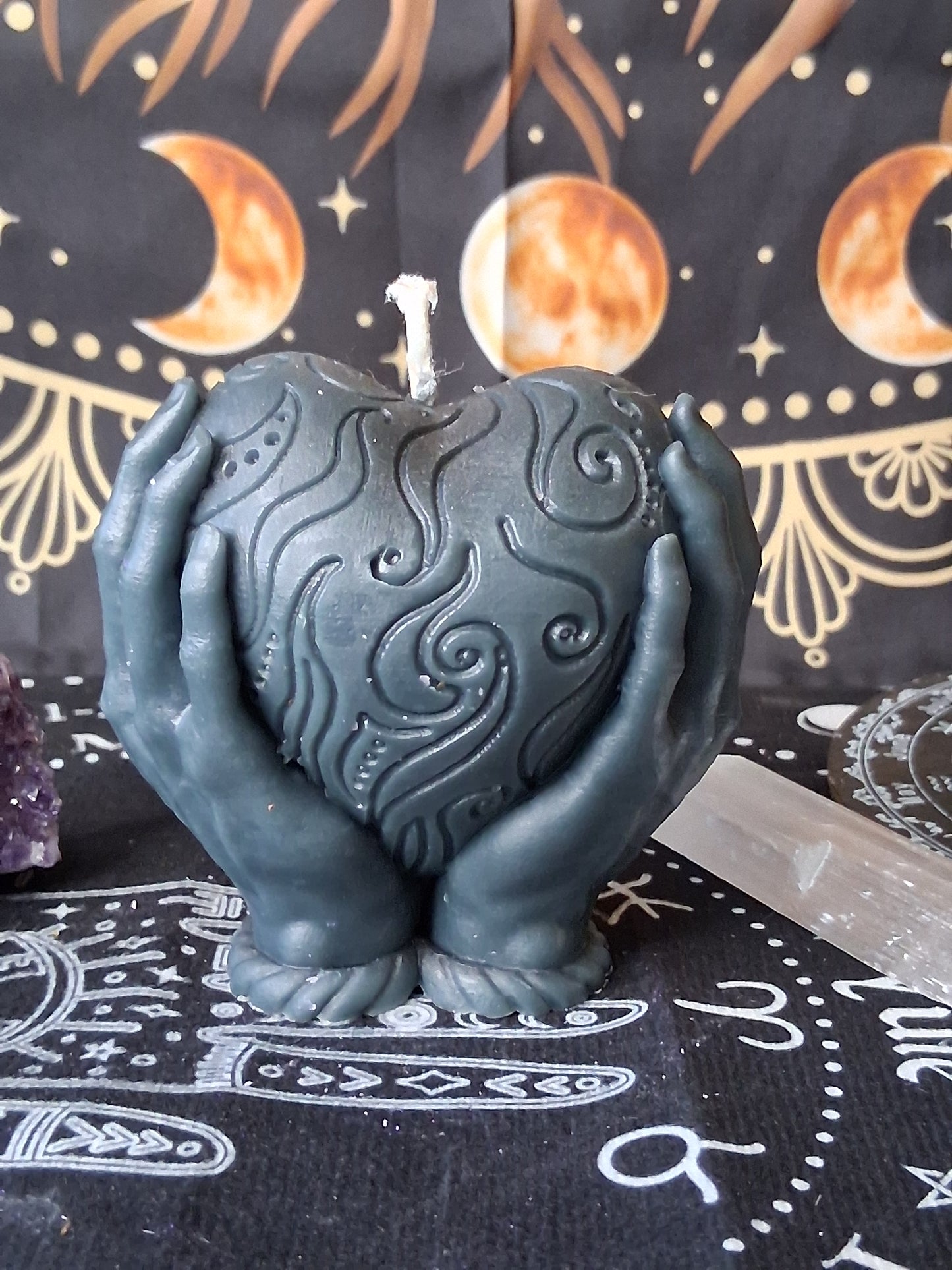 Heart in hands candle by Sacred Moon Candle Co with intricate swirling designs in dark gray