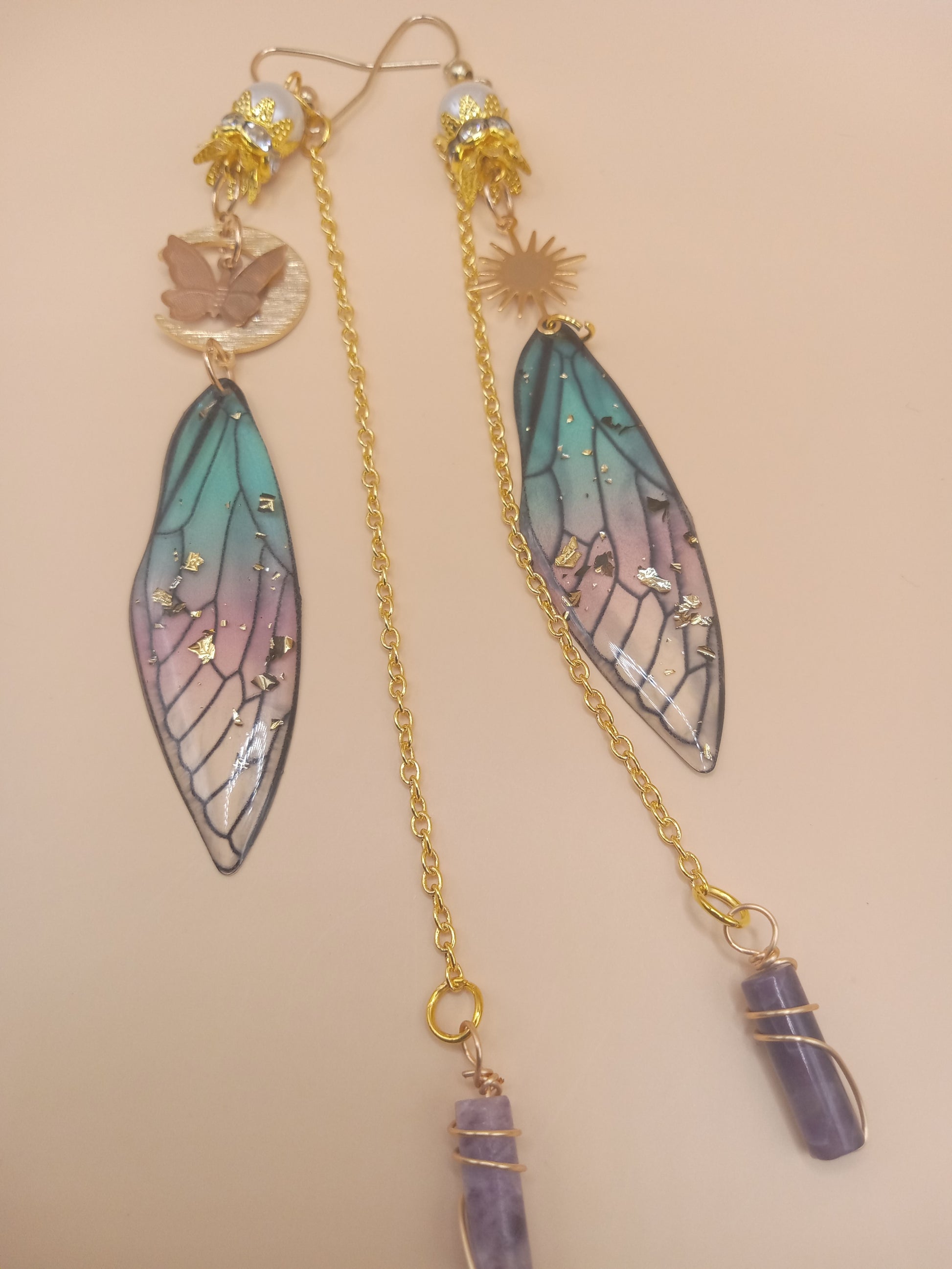 Sacred Moon Candle Co blue and violet fairy earrings with gold chains wing charms sun disc and amethyst drops