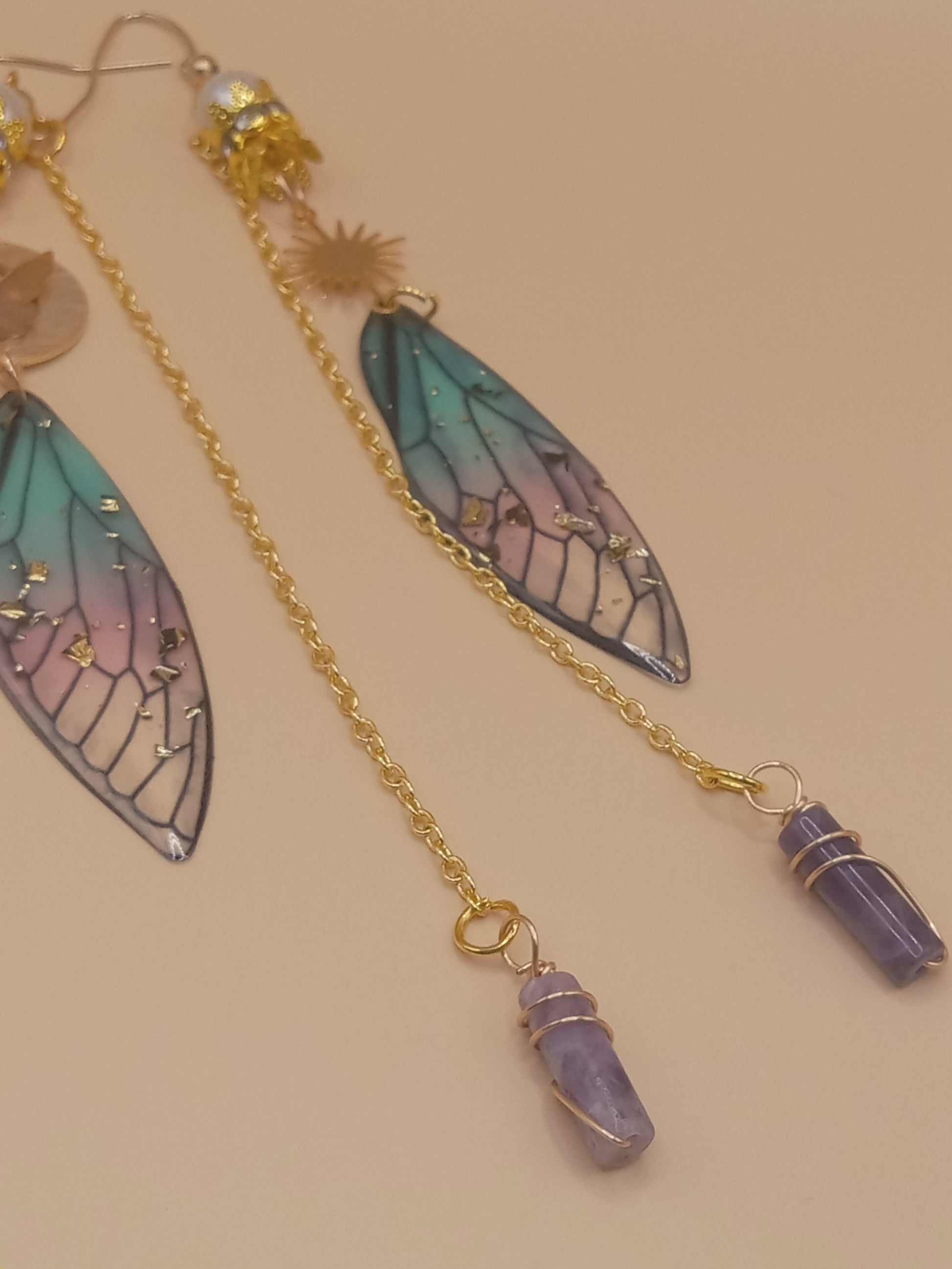 Delicate blue and violet fairy earrings by Sacred Moon Candle Co with gradient wing charms gold chains and lavender crystals
