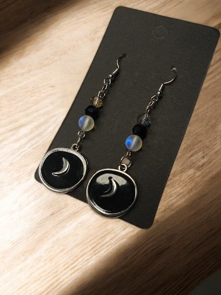 Sacred Moon Candle Co moon medallion earrings with crescent design and decorative beads on black card