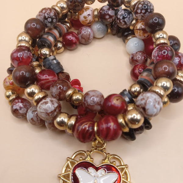 Sacred Moon Candle Co moth and flame bracelet stack with red and brown beads and gold accents
