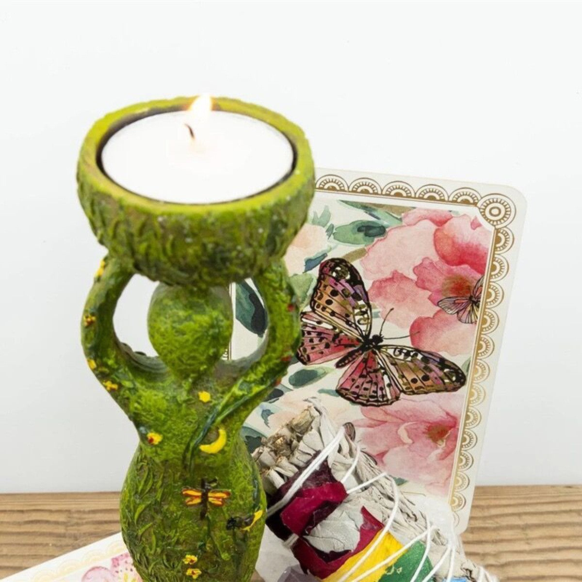 Green goddess altar statue candle holder with lit tealight floral card and smudge bundle
