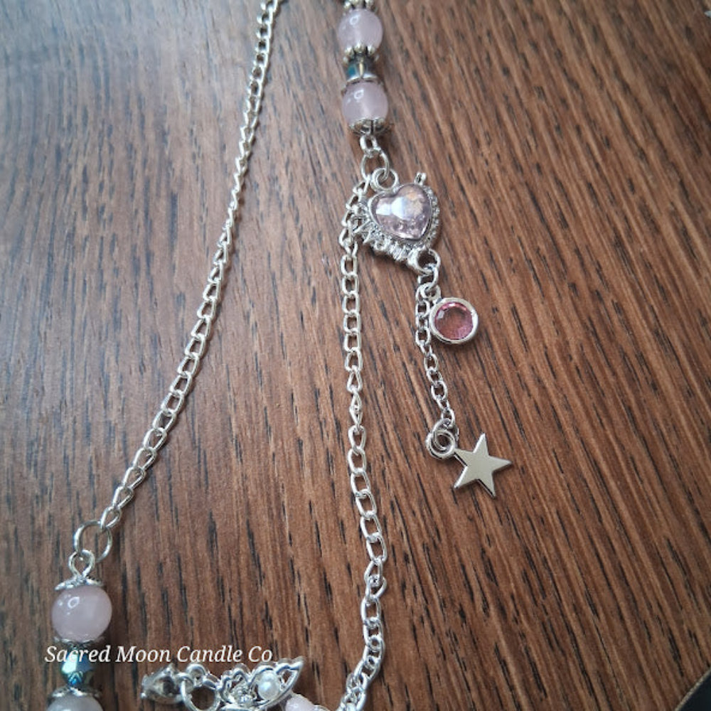 Rose quartz pendulum for divination with silver chain and star charm on wooden background