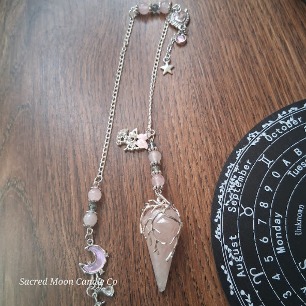 Sacred Moon Candle Co Seraphina's Heart Rose Quartz pendulum with silver chain and crystal beads on wooden surface