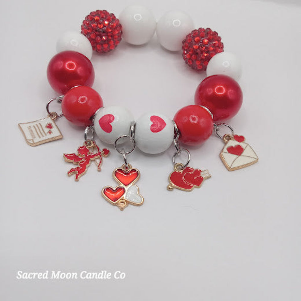 Cupid themed bubblegum beaded bracelet by Sacred Moon Candle Co with red and white beads and heart charms
