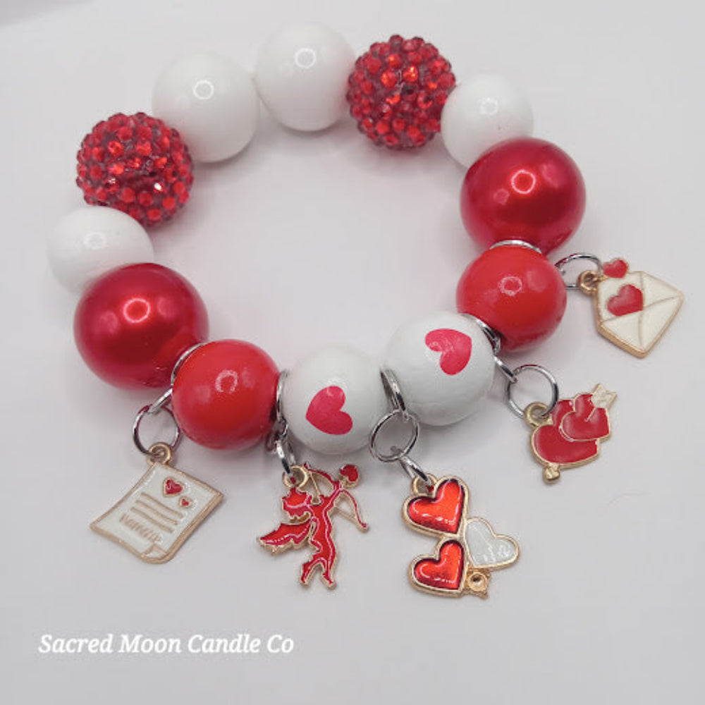 Cupid themed bubblegum beaded bracelet by Sacred Moon Candle Co with red and white beads and love charms