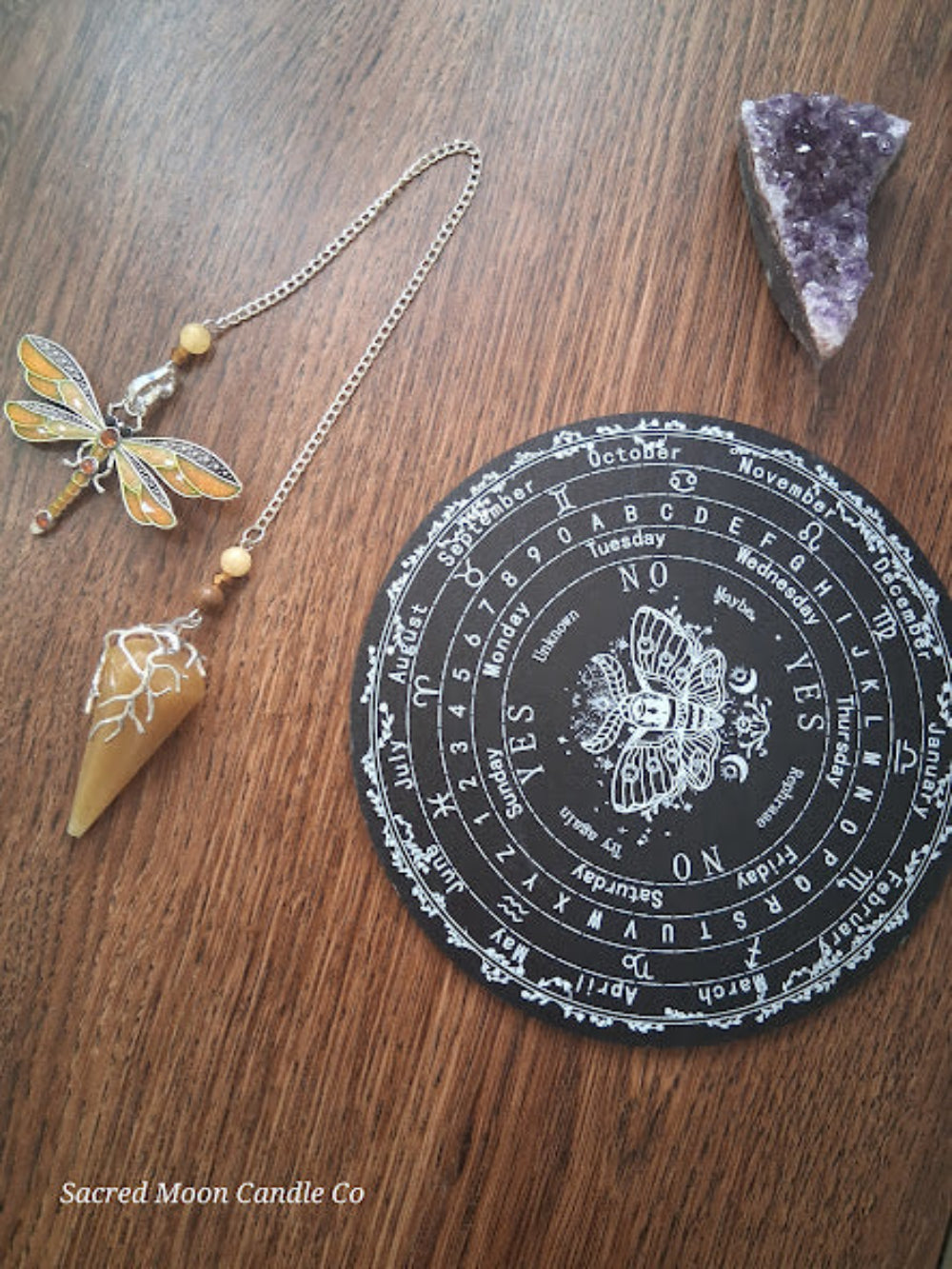 Golden healer quartz pendulum with dragonfly charm and black divination board from Sacred Moon Candle Co