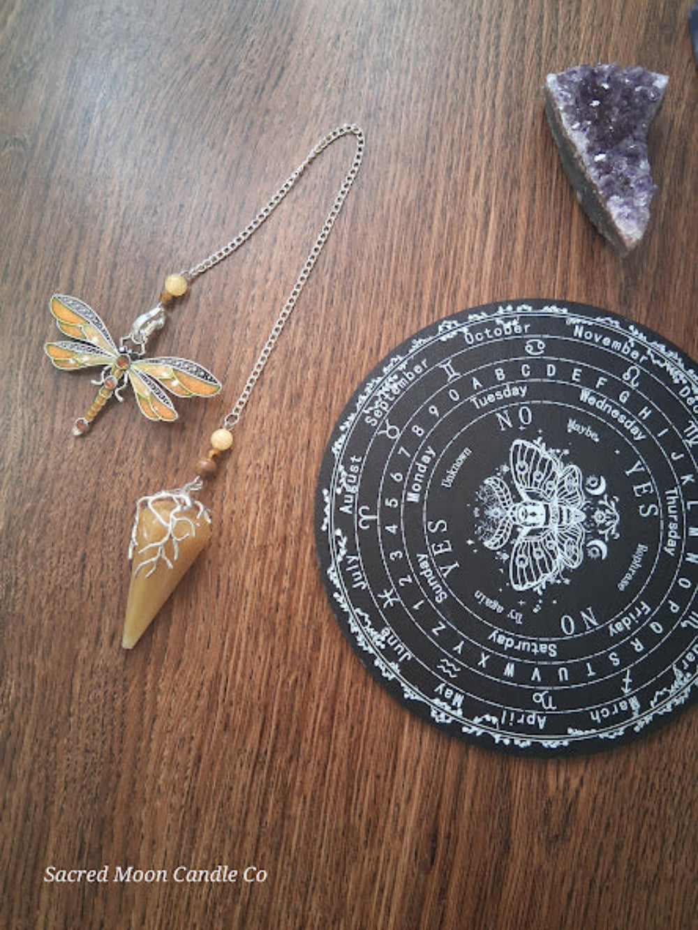 Golden healer quartz pendulum with dragonfly charm and divination board altar tools from Sacred Moon Candle Co